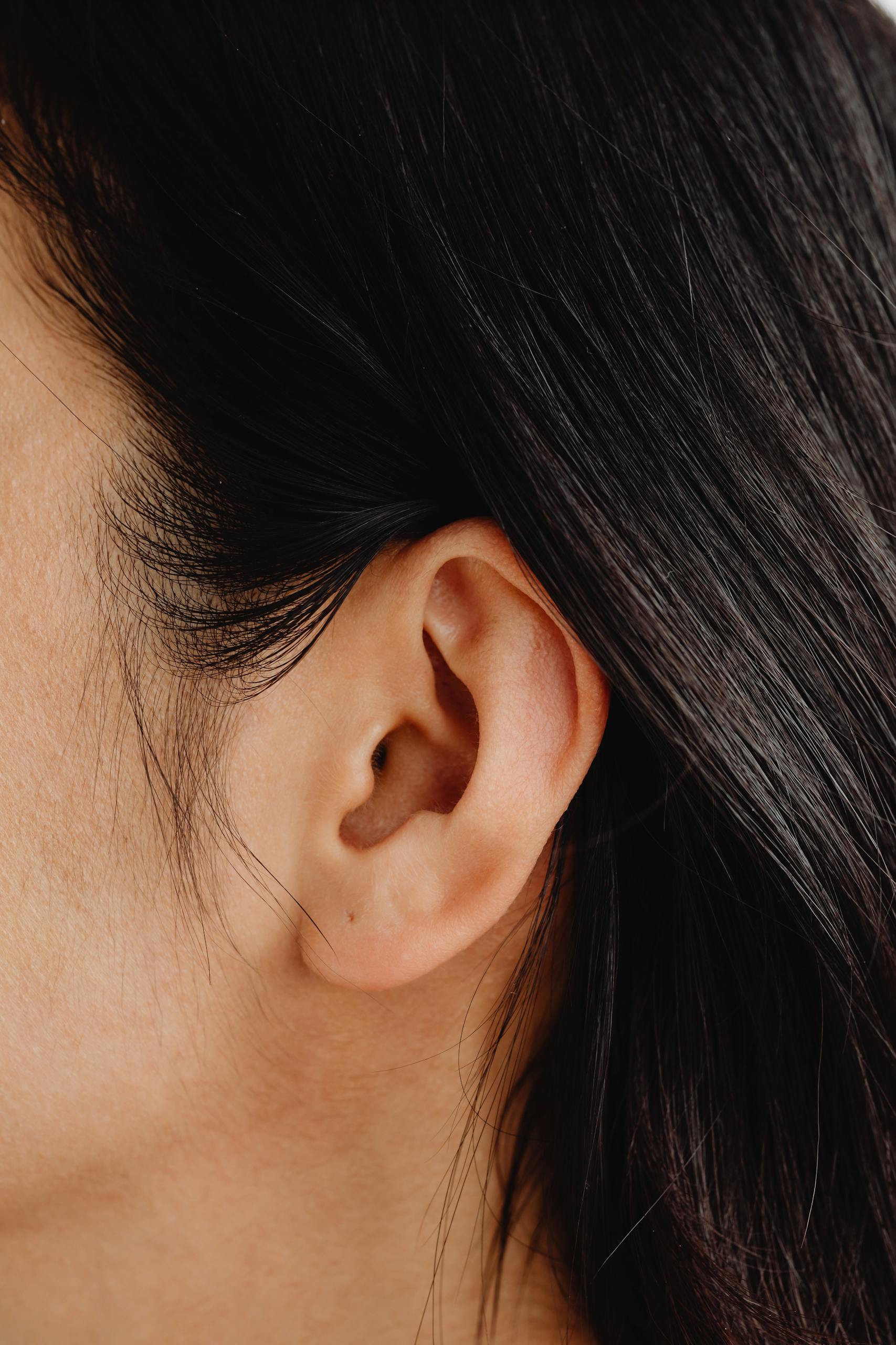 Detailed close-up image showcasing a human ear and dark hair.
